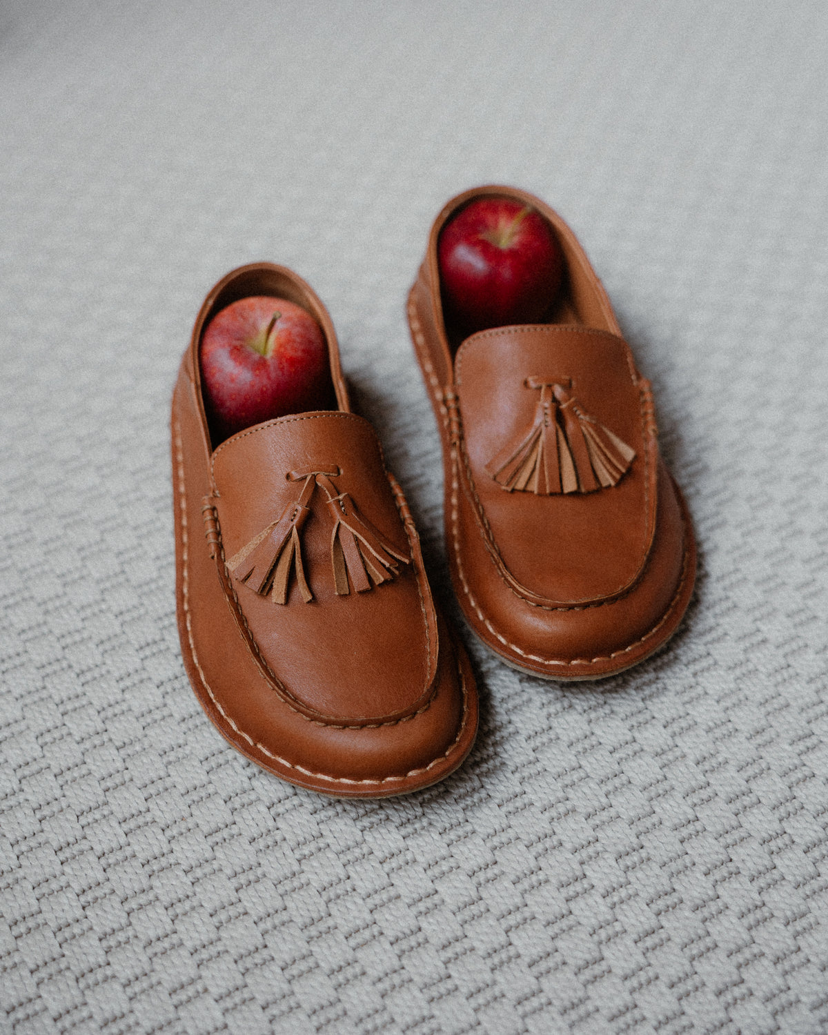 Par de mocasines TRIBECA Cognac Brown con una manzana roja dentro de cada uno