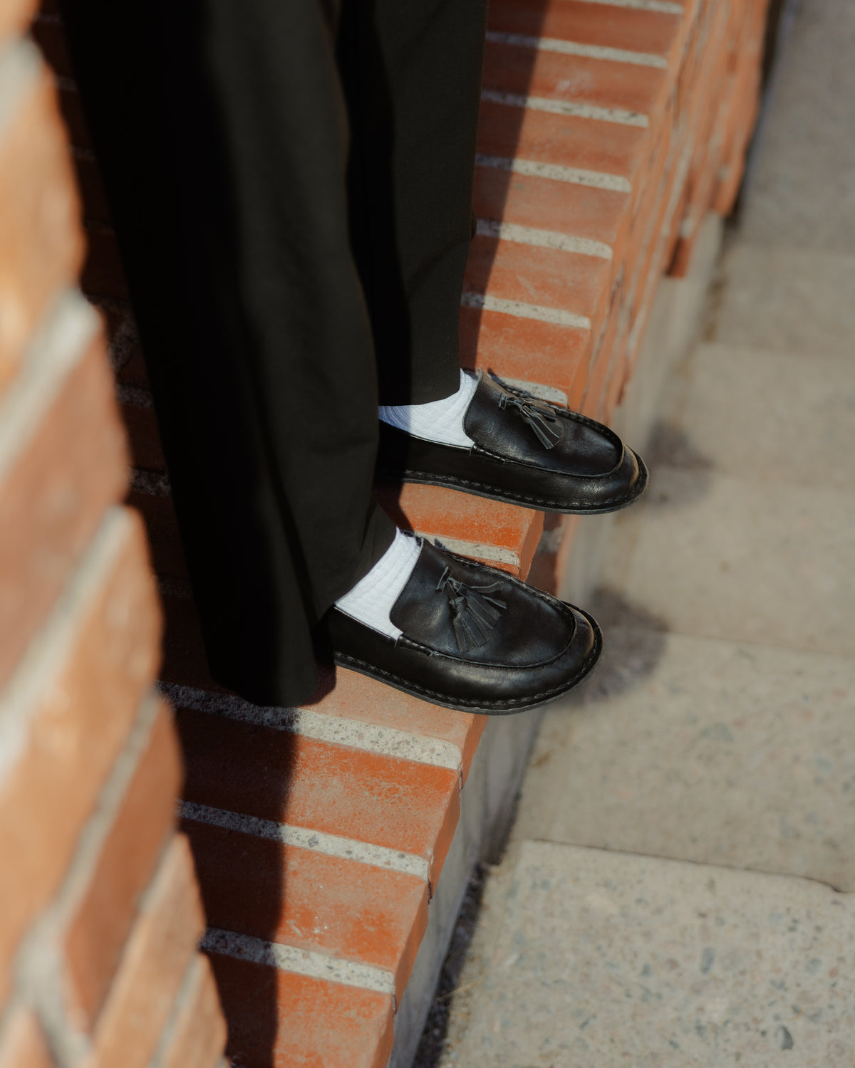 Mocasines TRIBECA Preto Black con calcetines blancos y pantalón negro sobre un escalón