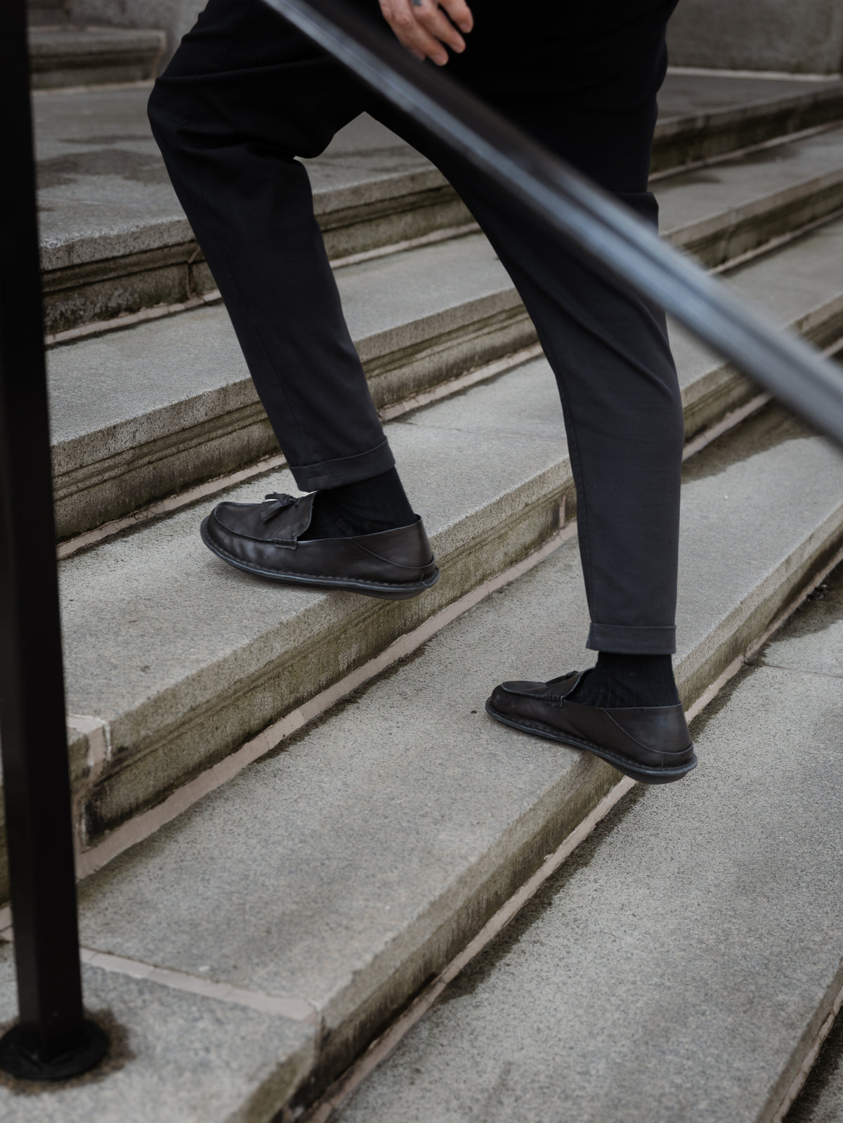 Persona subiendo una escalera con mocasines TRIBECA negros