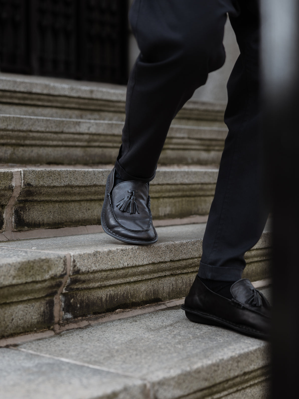 Persona bajando una escalera de piedra con mocasines TRIBECA negros